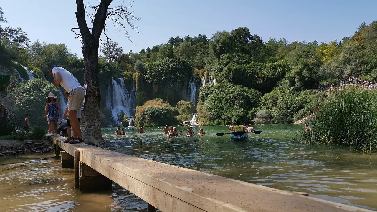 The broad horseshoe of Kravice waterfalls in Herzegovina, dozens of white cascades ringing a green pool