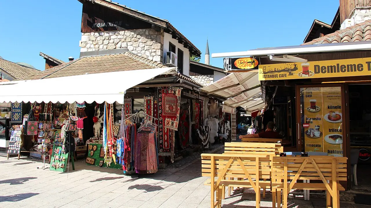 Souvenir shops and a café with a price board in the Baščaršija old bazaar of Sarajevo on a sunny day